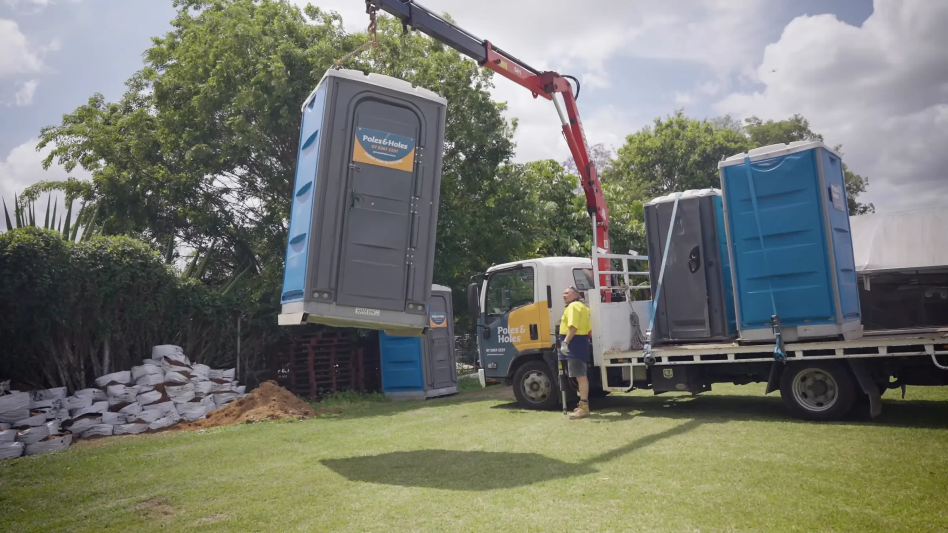 Poles and Holes delivering portable toilets by crane to a job site