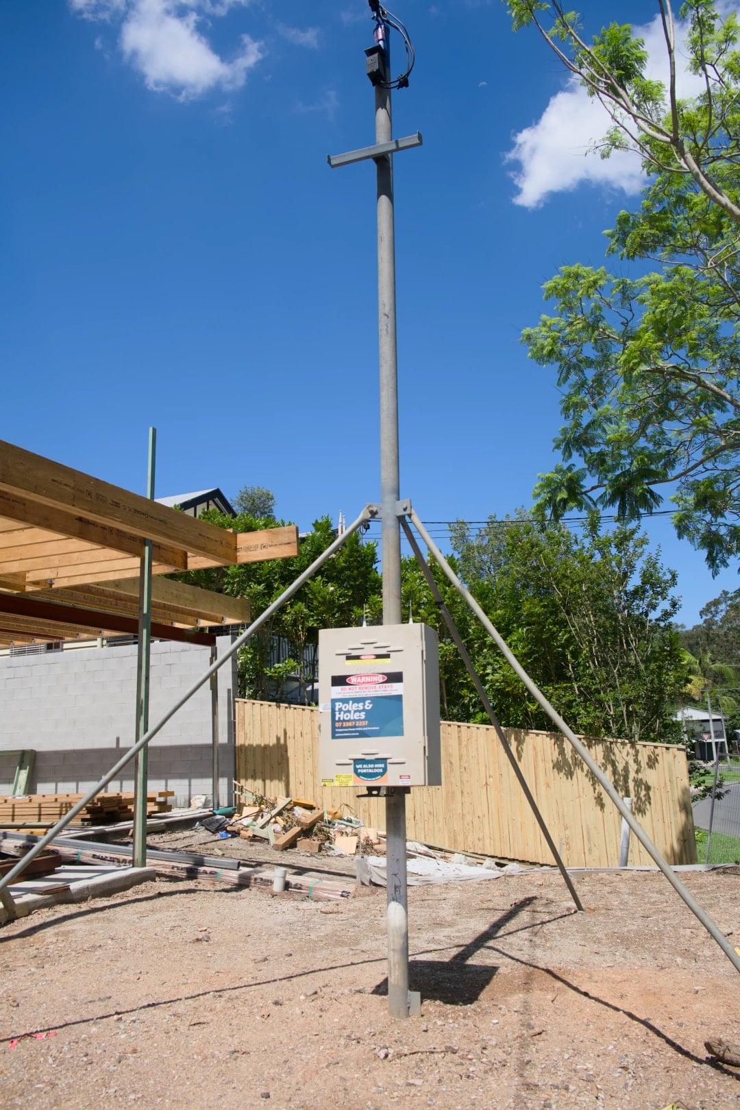 Temporary builder's power pole with metal stays on a Brisbane site