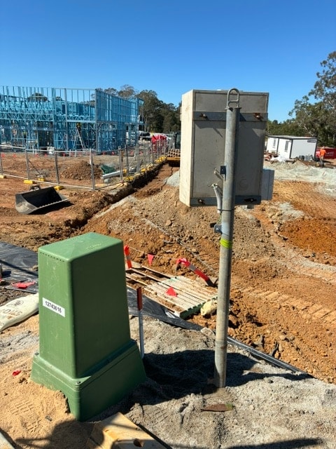 Underground temporary power connection on a Brisbane site: an Energex pillar and conduit in the trench beside the pole